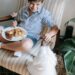 a boy playing with his dog while eating breakfast