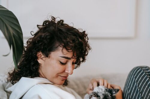 content woman caressing cat on couch